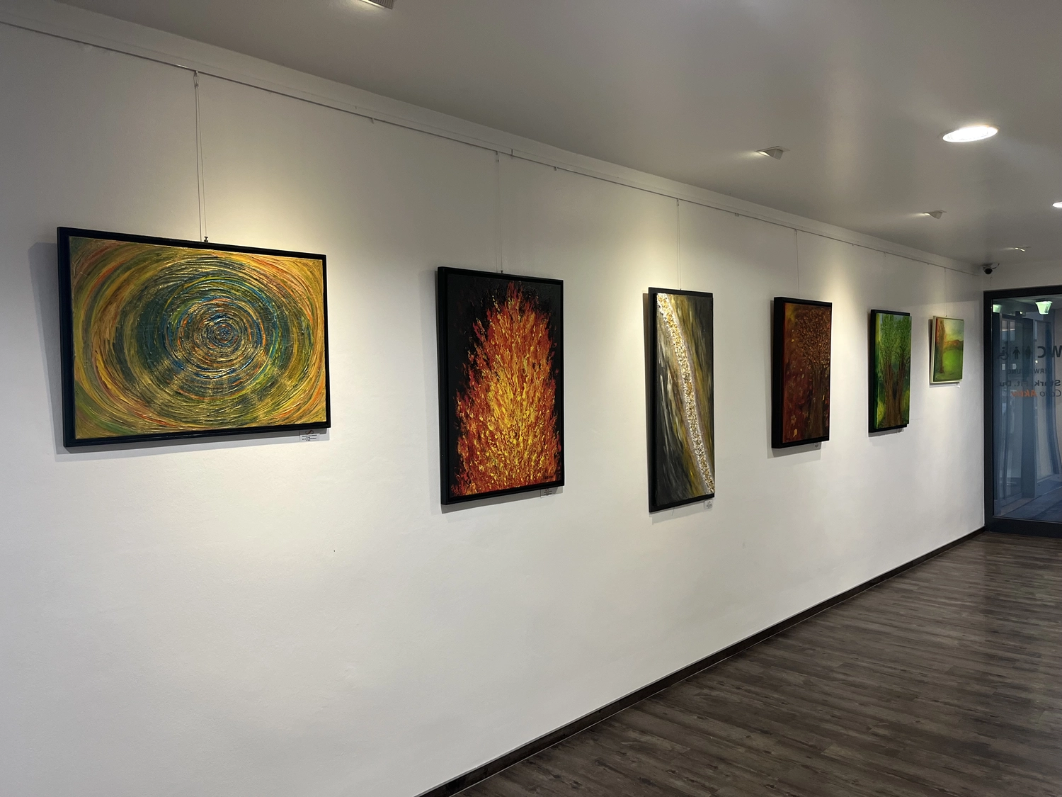 Hannelore Drees-Kiefhaber - Acrylmalerei von der Nordseeküste - Ein hell erleuchteter Flur in einer Kunstgalerie mit sechs gerahmten abstrakten Gemälden an einer weißen Wand und Holzboden.